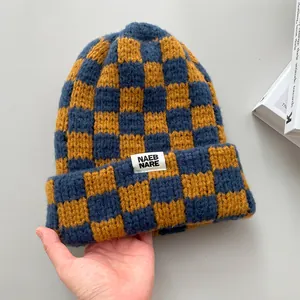 Close-up of a warm blue and yellow checkered knit beanie with a white label tag.