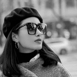 Close-up of a stylish Asian woman wearing a black wool beret in a retro city street