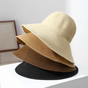 Detailed view of stacked wide-brim straw sun hats in cream, tan, brown and black.