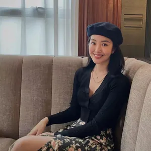 Elegant model wearing a black wool beret paired with a floral skirt in a cozy cafe