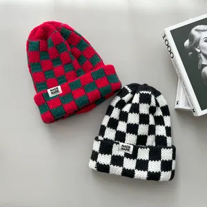 Detailed view showing the thick texture of red and black checkerboard knitted beanies.