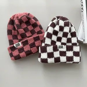 Close-up of thick knitted beanie hats with checkerboard pattern and logo patches