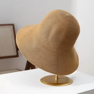 Close-up of premium wide brim straw sun hat for women on an elegant golden stand