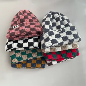 Detailed display of colorful checkered knitted beanies in various warm autumn hues