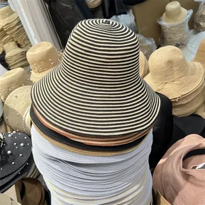 Detailed view of stacked striped foldable straw sun hats for women on a warehouse display