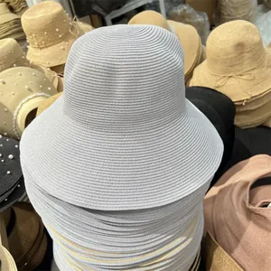 Detailed view of stacked light gray wide-brim straw sun hats for women summer travel