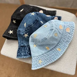 Detailed macro shot of children's denim bucket hats with shell and star embroidery