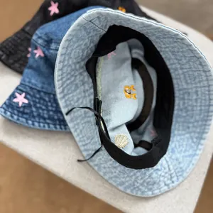 Detail view of children's denim bucket hat with embroidered starfish and shell motifs