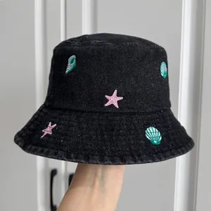 Detail view of children's black denim bucket hat with colorful sea shell embroidery