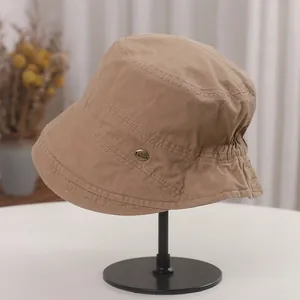 Close-up detail of khaki cotton bucket hat with retro pleated design and metal tag