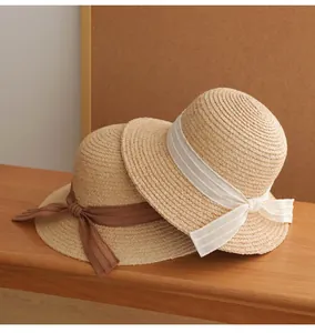 Detailed view of two French vintage straw sun hats with white and brown ribbon bows