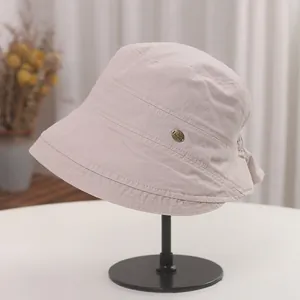 Detail view of a beige pleated Japanese style bucket hat on a black display stand