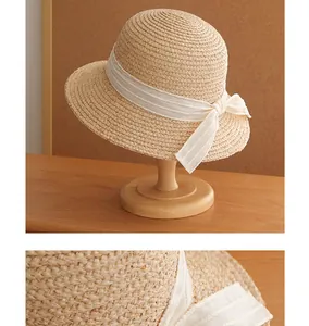 Close-up showing the intricate weave of a vintage straw hat with an elegant white ribbon bow