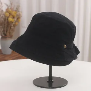Side profile detail of a black pleated cotton sun hat showing texture and button accent
