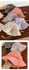 Detailed view of multiple colorful plaid bucket hats with bows on a wooden table surface