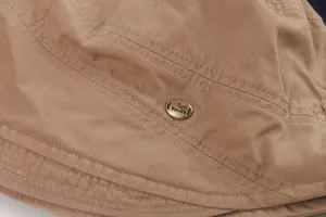 Close-up of retro tan bucket hat with fine stitching and a decorative Nature metal badge.