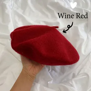 Detailed macro shot of a wine red wool beret held in hand against white background