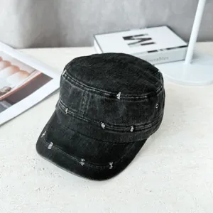 Detail view of a vintage distressed black denim flat top military cap for sun protection.