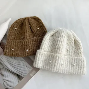 Detail view of winter knit beanies with elegant pearl embellishments in two colors
