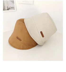 Vista dettagliata di due cappelli a secchiello minimalisti in marrone e beige testurizzati