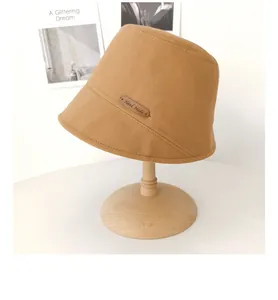 Vista dettagliata di un cappello da pescatore color cammello con toppa in pelle