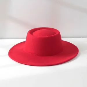 Close-up of a vintage red wool felt boater hat with a flat top and wide brim.
