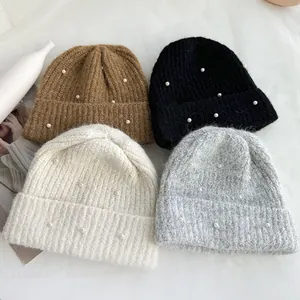 Group display of four warm winter knitted beanies with elegant pearl decorations