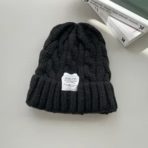 Dettaglio del berretto in maglia a trecce nero con etichetta moda bianca per l'inverno
