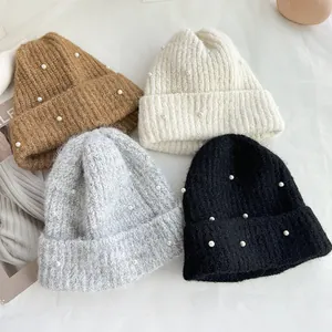 Detailed view of winter knit beanies in four colors featuring pearl embellishments