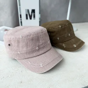 Close-up detail of two distressed flat-top military caps in pink and brown colors