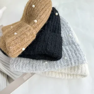 Detail of knitted beanies with elegant white pearl accents in various winter colors.