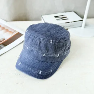 Detail view of a blue denim military cap with distressed ripped style elements