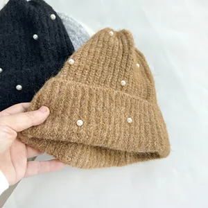 Close-up of a cozy brown knitted beanie featuring elegant pearl decorations