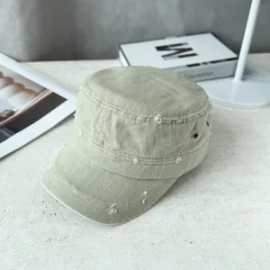 Detailed macro view showing distressed frayed holes on a sage green flat top military cadet cap