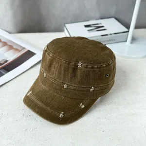 Close-up view of a brown military flat top cap featuring a unique distressed fabric design