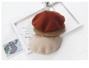 Three wool beret hats in warm autumn tones stacked together in a decorative white frame