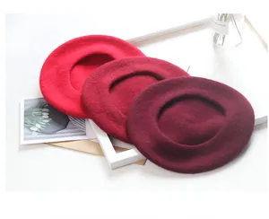 Macro view of three wool berets in different shades of red on white background