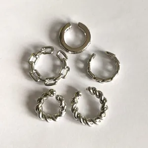 Macro view of five silver-plated alloy ear cuffs featuring twisted and chain link details.