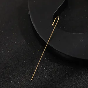 Detail view of a long minimalist gold ear crawler wrap earring on black background