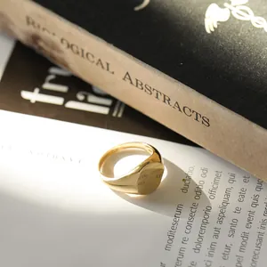 Close-up of minimalist gold-tone wide band signet ring with a round flat top