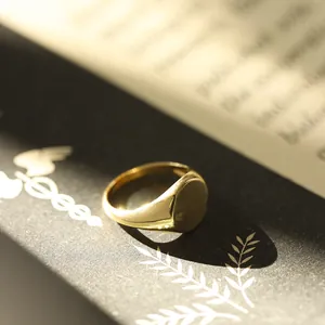 Close-up of a minimalist polished gold-colored signet ring on an artistic book background