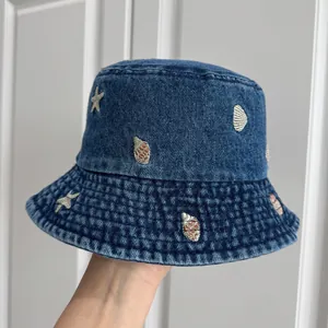 Detailed close-up showing seashell and starfish embroidery on a blue denim kids bucket hat