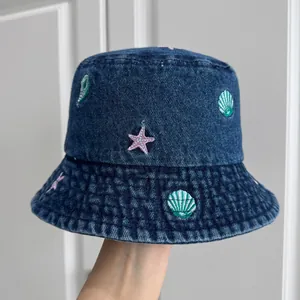 Detail of children's denim bucket hat with seashell and starfish embroidery motifs.