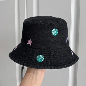Detailed view of children's denim bucket hat with embroidered seashells and starfish