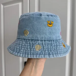 Detail view of children's denim bucket hat with embroidered sea shells and crabs