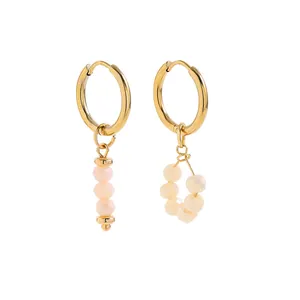 Detail view of asymmetric gold hoop earrings with pale pink faceted bead charms.