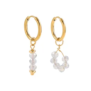 Detailed view of elegant gold asymmetric hoop earrings featuring clear faceted crystal beads