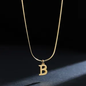Macro shot of a gold 18K plated stainless steel initial B pendant necklace on dark background