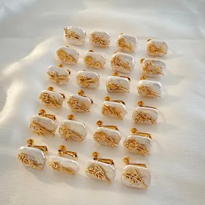 Detailed view of 12 month flower designs on natural baroque pearl earrings in gold