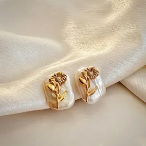 Macro detail of baroque pearl earrings featuring a delicate golden sunflower design